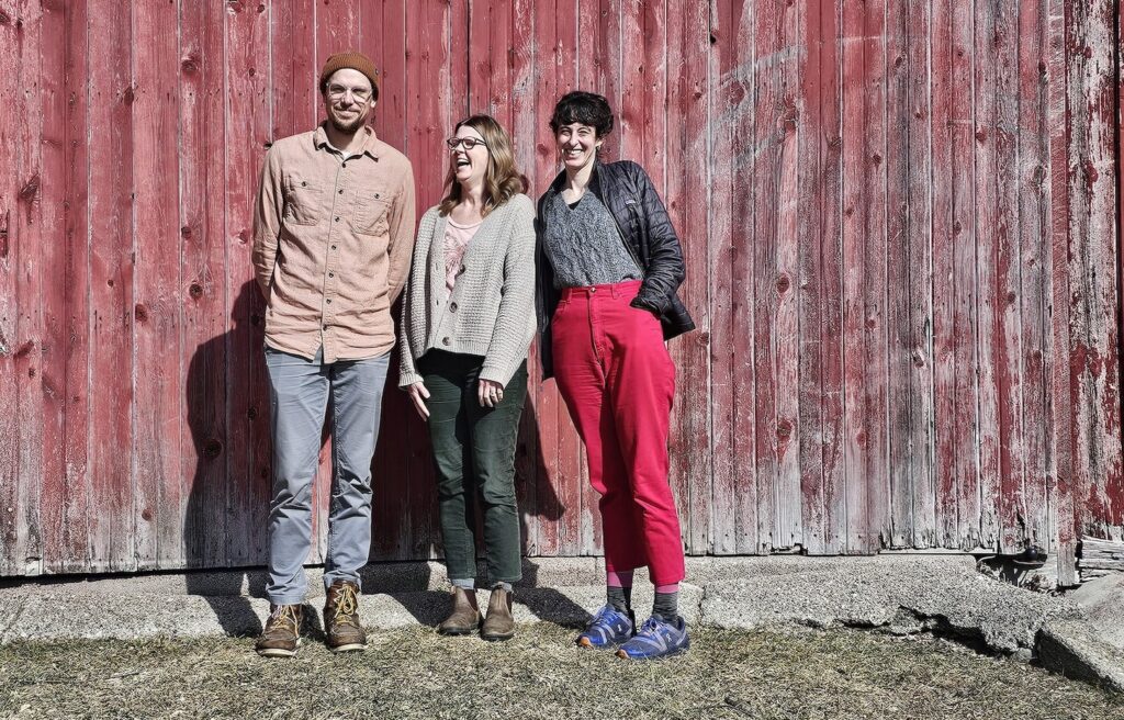 Three new co-directors standing together in front of red barn.